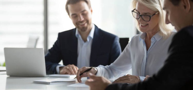 Kobieta i dwóch mężczyzn siedzą przy biurku i omawiają sprawy biznesowe – rejestracja spółki