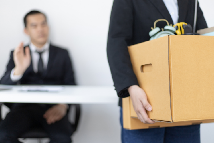 Mężczyzna wynosi w pudle w pude. W tle inny mu macha