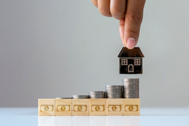 Stos monet, na którym stawiana jest miniatura domu