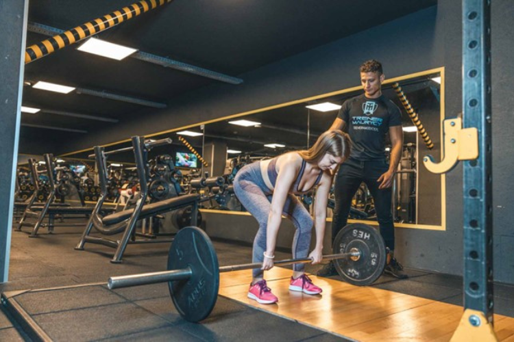 Kobieta ćwiczy z trenerem personalnym na siłowni