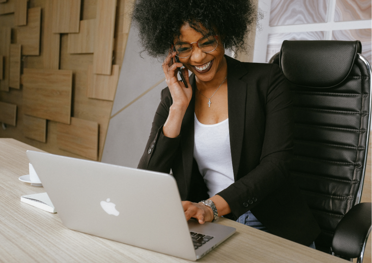 Kobieta siedzi przy laptopie i rozmawia przez telefon