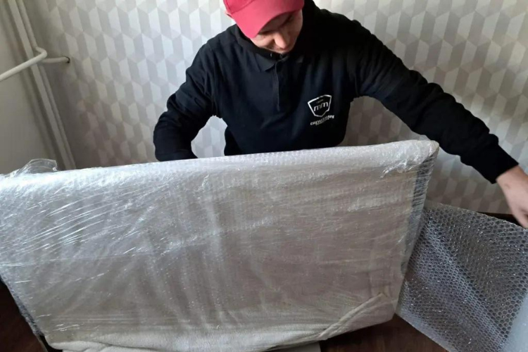 Przedstawiciel firmy transportowej zabezpiecza telewizor przed przeprowadzką