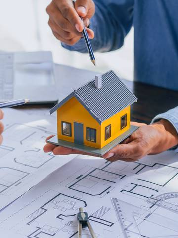 architekt pokazuje ręką model domu i projekt domu