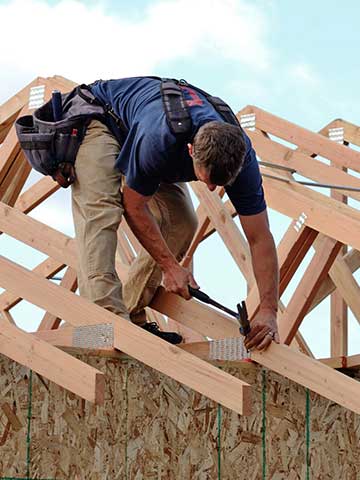 dekarz montuje krokwie dachowe na murłatach