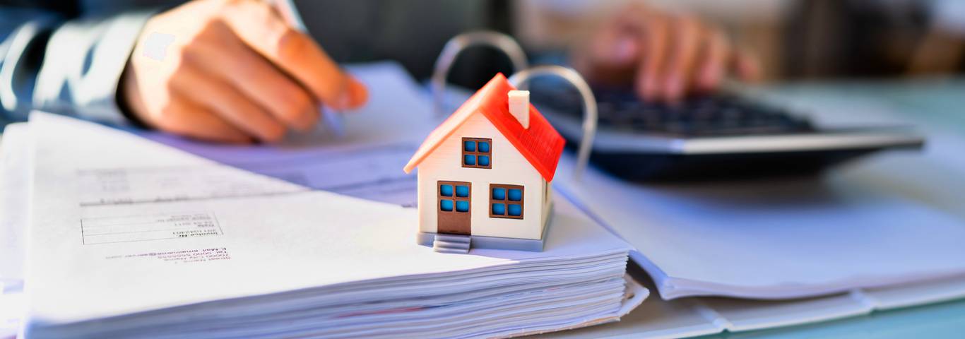 zbliżenie na model domu na dokumentach podatku od sprzedaży nieruchomości