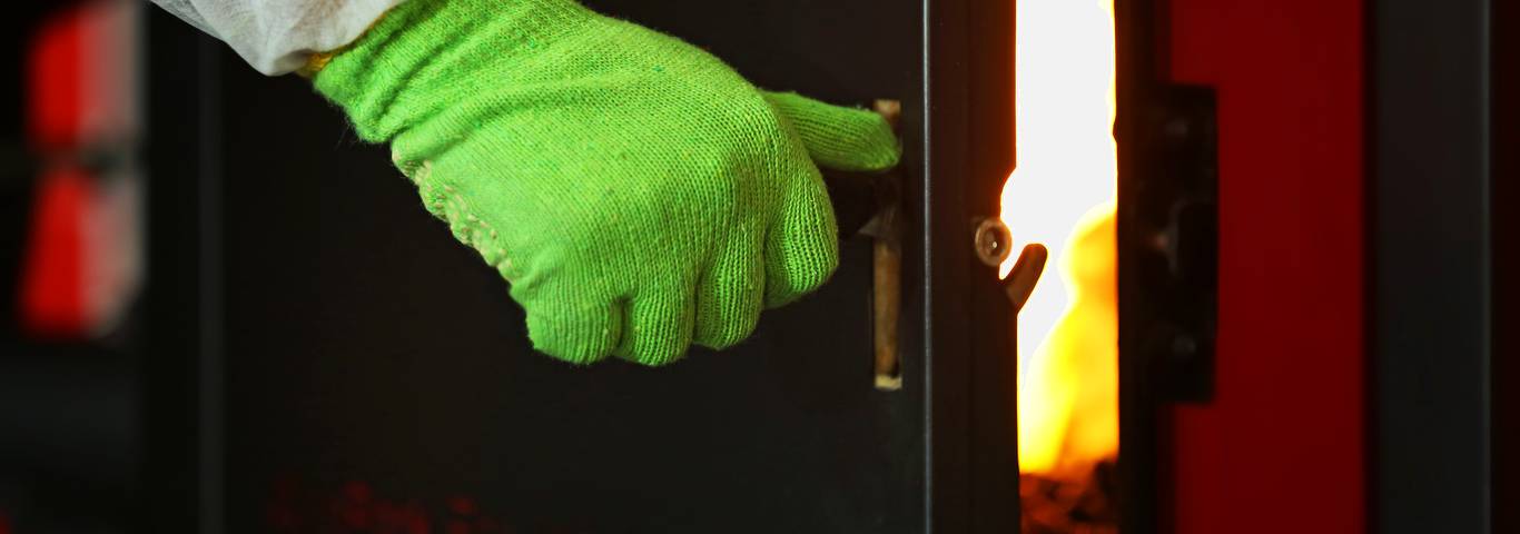 zbliżenie na rękę otwierającą drzwi kotła spalającego ekogroszek