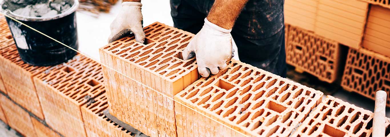 budowlaniec kładzie pustak ceramiczny na warstwę zaprawy